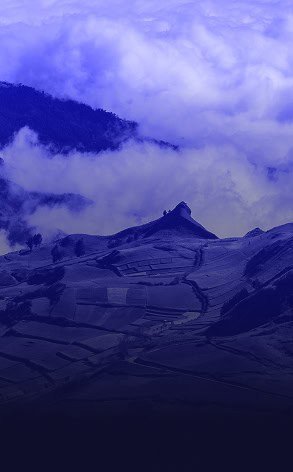 Vista aérea de un paisaje montañoso con nubes bajo un cielo azul profundo en Ecuador.