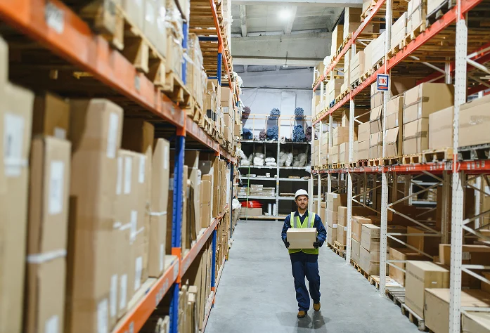 Un trabajador de una empresa de logística internacional carga un paquete en un almacén bien iluminado.