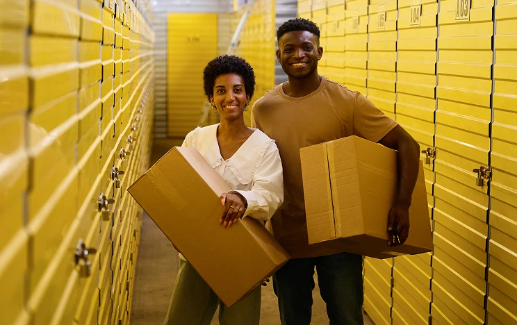 Dos personas colaborando en un área de almacenamiento con cajas de cartón.