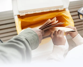 Persona abriendo un refrigerador abierto, sosteniendo un archivo en una mano y un libro en la otra.