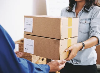 Persona en un entorno de trabajo con cajas de paquetería y un reloj en la muñeca, sugiriendo eficiencia y cumplimiento de plazos en envíos internacionales desde Ecuador.