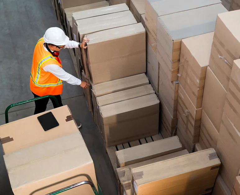 Trabajador en un almacén moviendo cajas, indicando un proceso de logística activo.