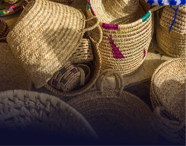 Una colección de cestas tejidas y sombreros dispuestos de manera desordenada, sugiriendo una venta en un mercado o feria.