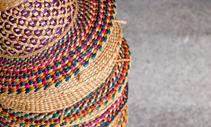 Un sombrero tejido de colores con un amplio ala, colocado sobre una superficie gris.