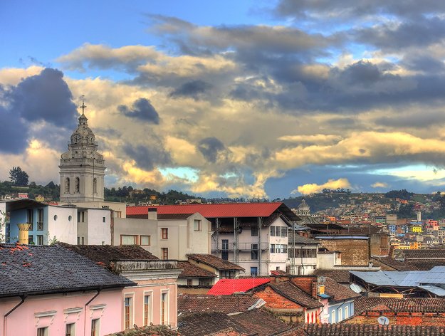 Una ciudad vibrante con edificios blancos y techos rojos, ubicada en una colina con un cielo nublado.